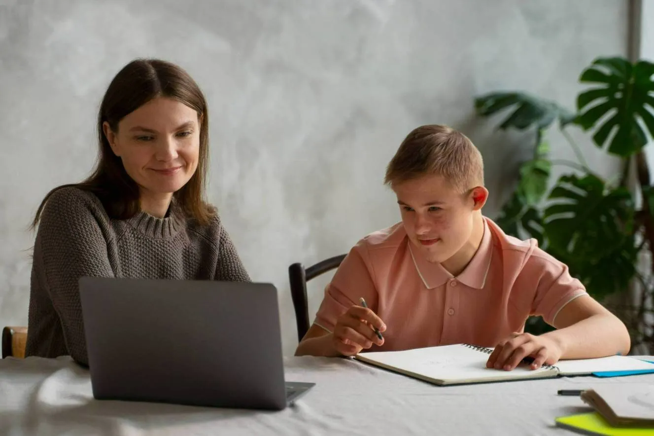 A smiling student with special needs learning at home with his mother